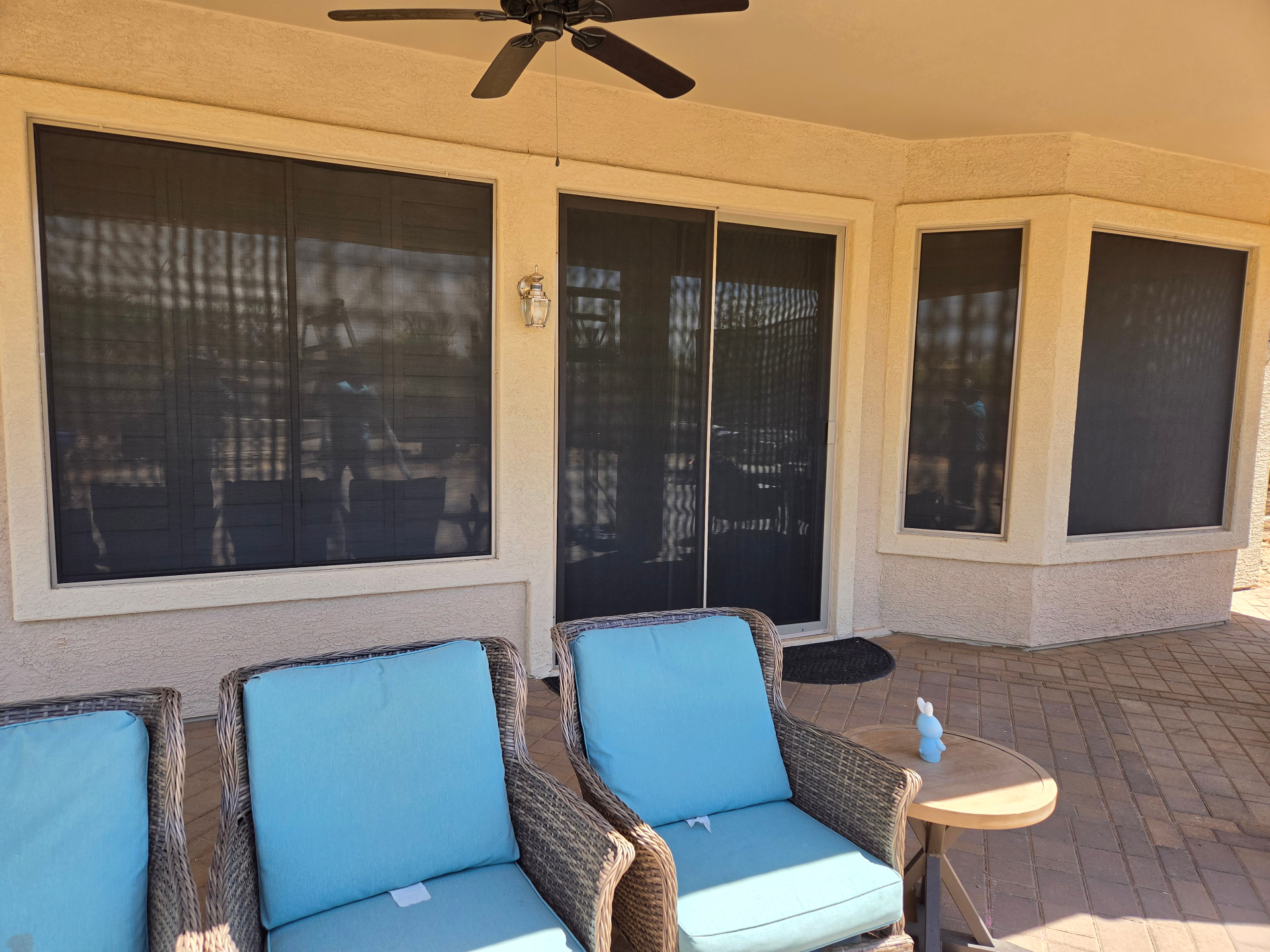 Covered patio with sun screens and blue wicker chairs