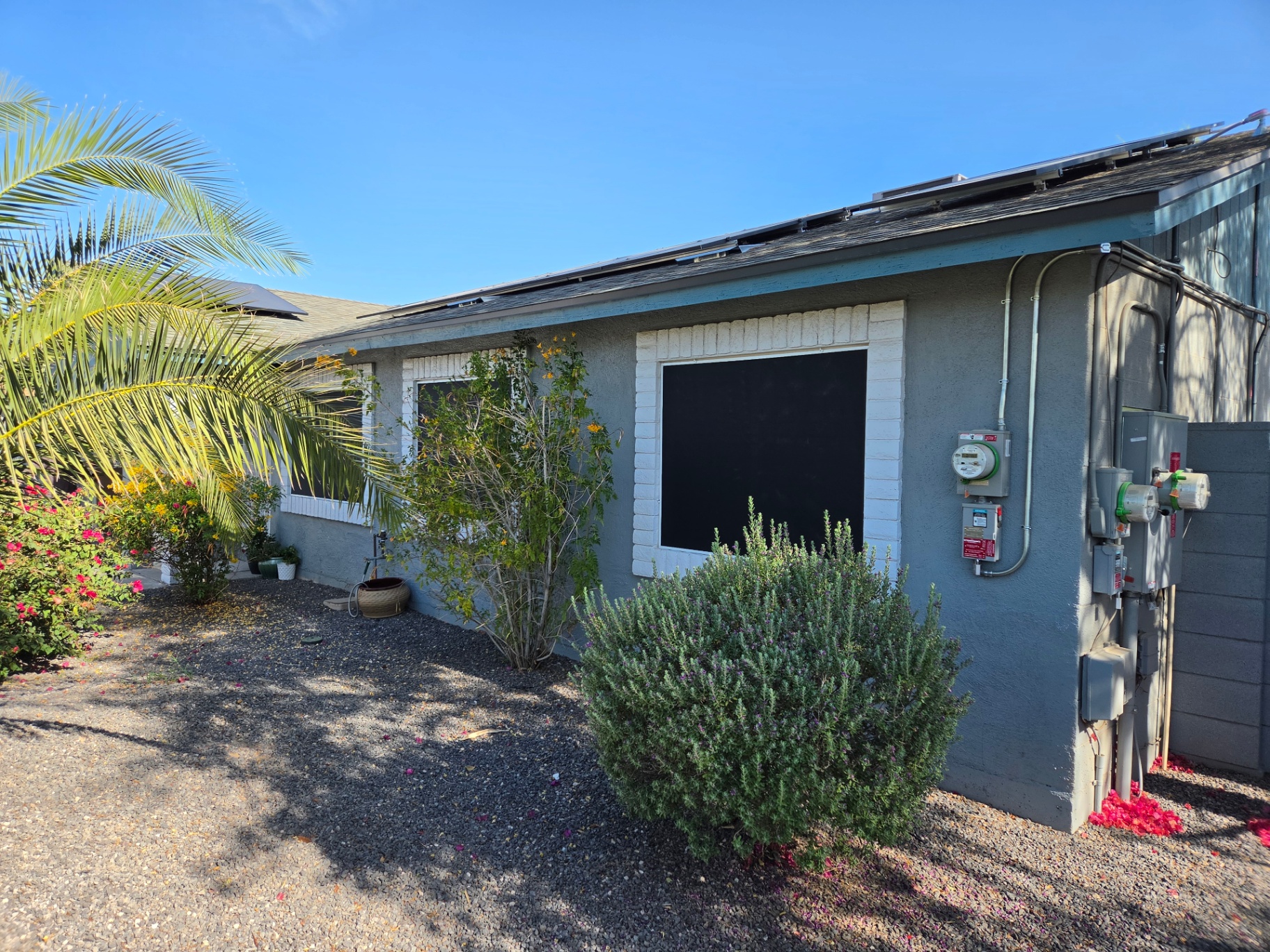 Side yard window with black sun screen on gray stucco home